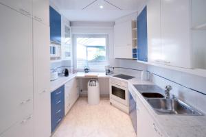 una cucina bianca con armadi blu e lavandino di Aparthome L.I.N.Z. a Bergham