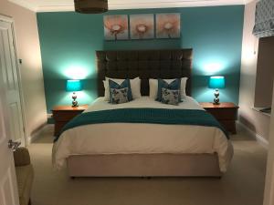 een slaapkamer met een groot bed met 2 lampen bij Crofthead Farm House in Tarbolton