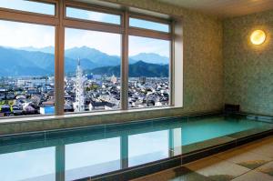 a swimming pool in a building with a view of a city at Saijo Urban Hotel in Saijo