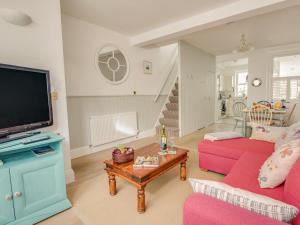 a living room with pink furniture and a flat screen tv at Seahorse Cottage in Weymouth