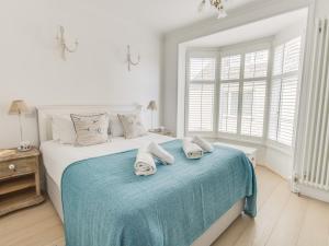 a white bedroom with a bed with towels on it at Seahorse Cottage in Weymouth