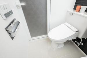 een witte badkamer met een toilet en een douche bij M's Hotel Nijojo Oike in Kyoto