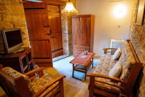 a living room with a couch and a tv and a table at Constantias stone houses in Lofou