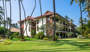 a house with palm trees in front of it at Eskala Hotels and Resorts in Ngwesaung