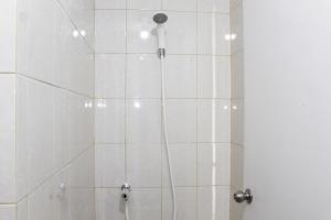 a shower with a white tile wall and a shower head at Minimalist Studio Apartment at Poris 88 with City View By Travelio in Tangerang +5 photos