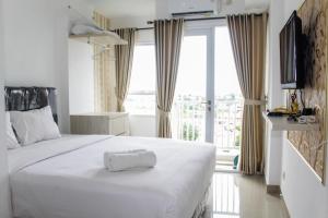 a bedroom with a large white bed and a window at Minimalist Studio Apartment at Poris 88 with City View By Travelio in Tangerang