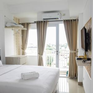 a hotel room with a bed and a large window at Minimalist Studio Apartment at Poris 88 with City View By Travelio in Tangerang