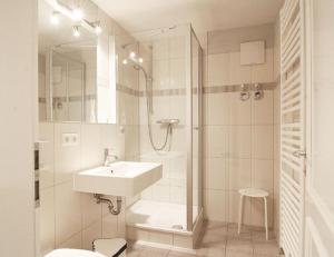 ein weißes Bad mit einem Waschbecken und einer Dusche in der Unterkunft Appartmenthaus Villa Laura in Kühlungsborn