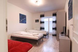 1 Schlafzimmer mit 2 Betten und einem roten Sofa in der Unterkunft Appartmenthaus Villa Laura in Kühlungsborn