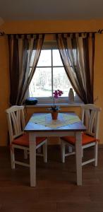 a dining room table with two chairs and a window at Ferienwohnung Wasserlilie in Kolonie