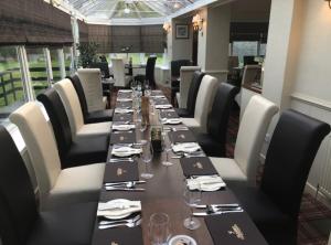 uma longa sala de jantar com uma longa mesa e cadeiras em Glazert Country House Hotel em Lennoxtown