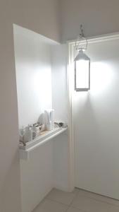 Gouritz Guesthouse في Gouritzmond: غرفة بيضاء مع ضوء يتدلى من الجدار