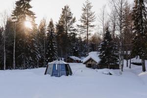 a tent in the snow in front of a cabin at Ollero Eco Lodge (including a glass igloo) in Rovaniemi