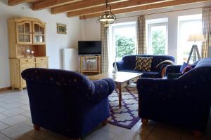 a living room with blue chairs and a table at Ferienhof Land-Idyll in Osterhever