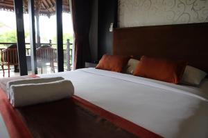Taman Agung Hotel في سانور: غرفة نوم مع سرير أبيض كبير مع وسائد برتقالية