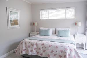 um quarto branco com uma cama e duas mesas de cabeceira em Conifer Beach House em Port Elizabeth