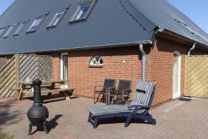 a brick house with a smoker and a chair and a table at Ferienhof Land-Idyll in Osterhever