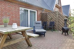 a wooden picnic table and chairs on a brick patio at Ferienhof Land-Idyll in Osterhever