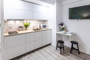 una cocina con armarios blancos y 2 taburetes en GoToSeville Molviedro Apartments, en Sevilla