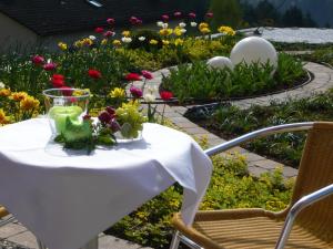 a table in a garden with a drink and flowers at Hotel Hochwald in Bad Liebenzell