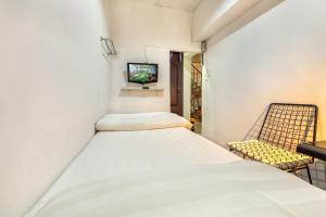 een kleine kamer met een bed en een stoel bij Sloth Hostel Khaosan in Bangkok