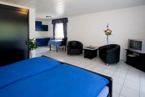a bedroom with a blue bed and chairs and a tv at Pension Mosella , Wohnung mit Balkon und Moselblick in Sankt Aldegund