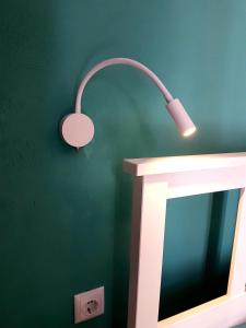 a light on a green wall next to a mirror at Issos Studios in Agios Georgios