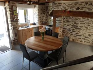 a kitchen with a wooden table and chairs at LA MAISON DE JADE in Soursac