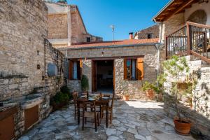 a stone house with a table and chairs in a courtyard at Constantias stone houses in Lofou