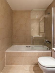 y baño con bañera, aseo y lavamanos. en Homing Barcelona 101, en Barcelona