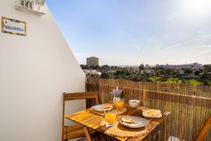 a wooden table with plates and glasses on a balcony at APARTAMENTO COR DO MAR - Sunny, Clean and spacious apartment with sea view, in Alvor - very close walking distance to the beach and Alvor Village in Alvor