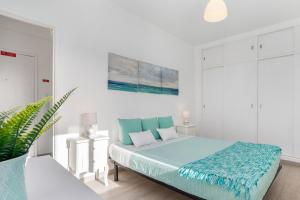 a white bedroom with a large bed with blue sheets at APARTAMENTO COR DO MAR - Sunny, Clean and spacious apartment with sea view, in Alvor - very close walking distance to the beach and Alvor Village in Alvor