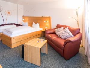 a bedroom with a bed and a couch and a chair at Hotel Hochwald in Bad Liebenzell