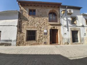 a stone building with a door and a balcony at La casina de Carmina in Arroyomolinos de Montánchez