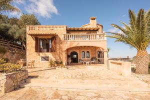 una casa de piedra con una palmera delante de ella en Finca Roca, en Es Carritxo