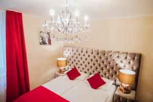 Schlafzimmer mit einem Bett mit roten Kissen und einem Kronleuchter in der Unterkunft Hotel CULT Hamburg in Hamburg