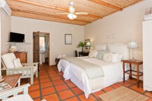 ein Schlafzimmer mit einem großen weißen Bett und einem Tisch in der Unterkunft Oue Werf Country House in Oudtshoorn
