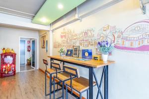 a dining room with a table and chairs with a mural on the wall at Sleep Dee Hostel in Bangkok