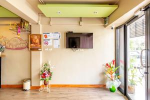 a room with a tv and flowers on the wall at Sleep Dee Hostel in Bangkok +67 photos