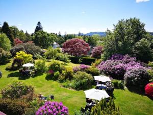 a garden with tables and umbrellas and flowers at Lindeth Howe in Bowness-on-Windermere
