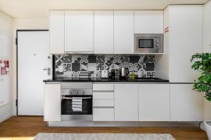 a kitchen with white cabinets and a microwave at WHome | Alcântara Smart Studio in Lisbon