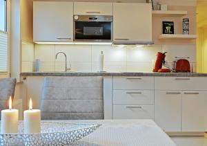 a kitchen with white cabinets and a table with two candles at Thiel Apartments in Krefeld