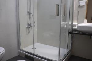 une douche avec une porte vitrée à côté d'un lavabo dans l'établissement Hotel Belém Tejo - Setubalense, à Lisbonne
