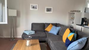 a living room with a gray couch with colorful pillows at Ferienwohnung-Strandspaziergang, grosse Wohnung in Börgerende-Rethwisch