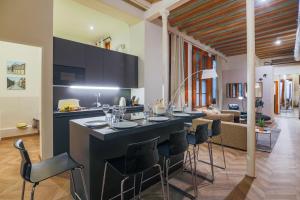 a kitchen with a bar with chairs and a living room at Avinyó- New Listing -Spacious Loft in the Gothic Quarter! in Barcelona