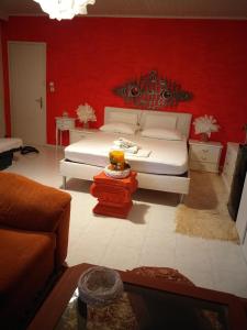 1 dormitorio con cama blanca y pared roja en Roulas Cozy Apartments, en Artemida