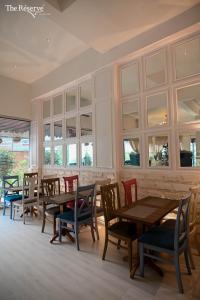 un restaurante con mesas y sillas de madera y ventanas en The Reserve Boutique Hotel en Karachi