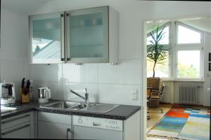 a white kitchen with a sink and a window at Haus Gies in Wasserburg am Bodensee