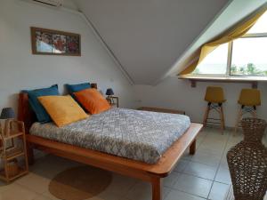 1 dormitorio con 1 cama con almohadas de color naranja y azul en La Kaz du Lagon, en Le Gosier
