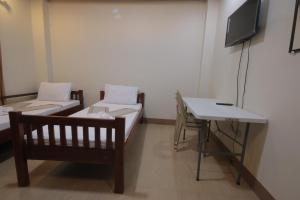 Cette chambre comprend 2 lits, une table et une télévision. dans l'établissement Monte casa de Rico, à Vigan